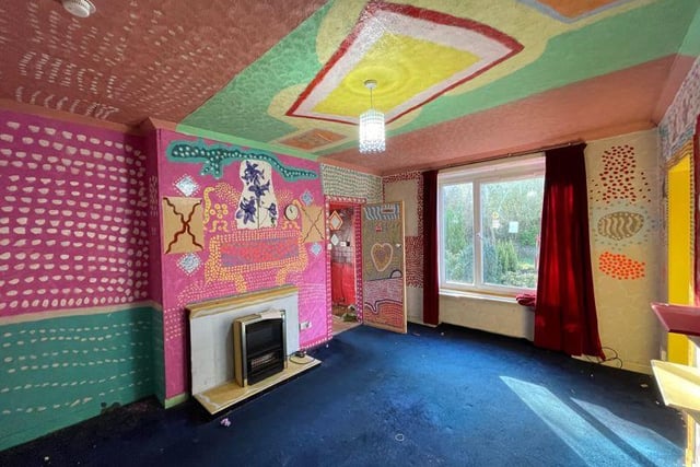 The living room walls and ceiling are covered in colourful artwork.