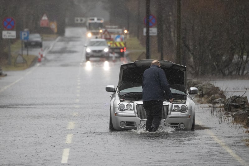 A motorist gets stuck in flood water along the A84