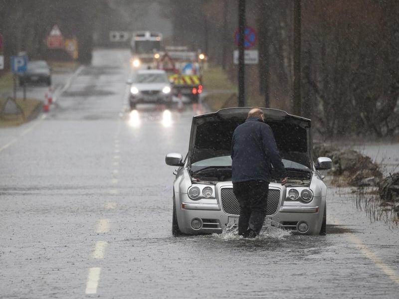 A motorist gets stuck in flood water along the A84