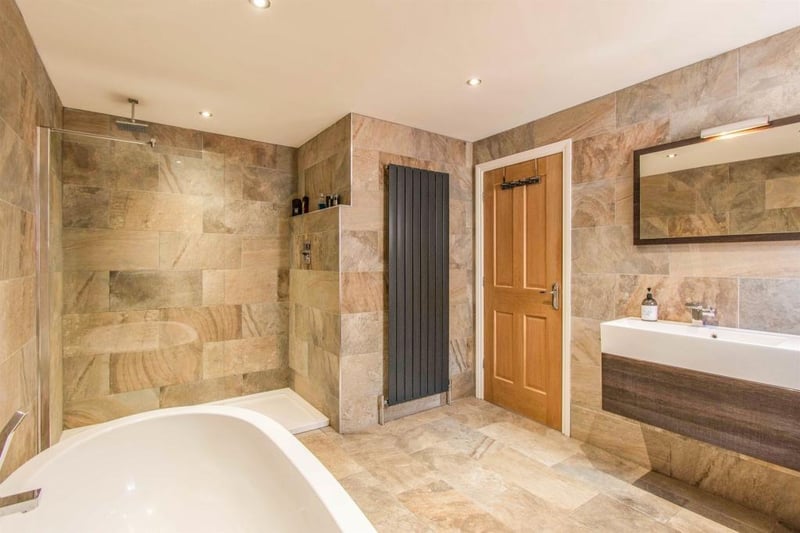 A deluxe bathroom suite fitted with a WC, a wash hand basin fitted onto a vanity unit a free standing double ended bath and a walk in double premium ceiling chrome square thermostatic shower.
