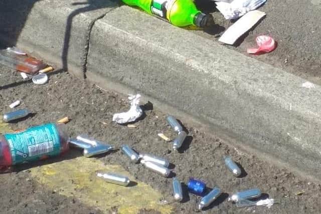 Silver nitrous oxide canisters amongst other litter dropped on the street.