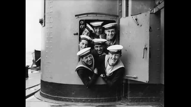 September 1928:  A group of sailors trying to squeeze out of a small door aboard the HMS Hood during naval manoeuvres.  (Photo by Fox Photos/Getty Images)