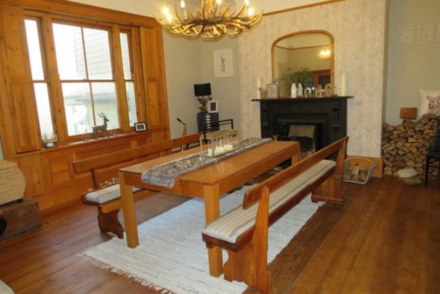 The spacious dining room impresses with its original fireplace with tiled hearth.