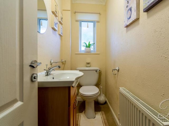 The bungalow's toilet is on the ground floor and comprises a low-flush WC, wash basin with storage, central-heating radiator and opaque window to the front.
