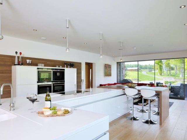 The kitchen is contemporary in design, with fitted cupboards and appliances, and features a breakfast bar area which looks out onto the outdoor patio.