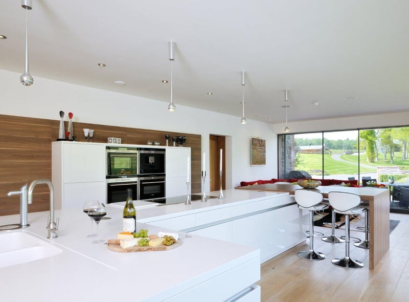 The kitchen is contemporary in design, with fitted cupboards and appliances, and features a breakfast bar area which looks out onto the outdoor patio.