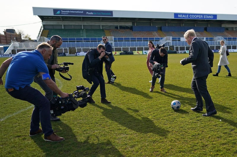 Britain's Prime Minister Boris Johnson (R) demonstrates his football skills to members of the media on a visit to Hartlepool United Football Club as he campaigns on behalf of Conservative Party candidate Jill Mortimer in Hartlepool, north-east England on April 23, 2021, ahead of the 2021 Hartlepool by-election to be held on May 6.