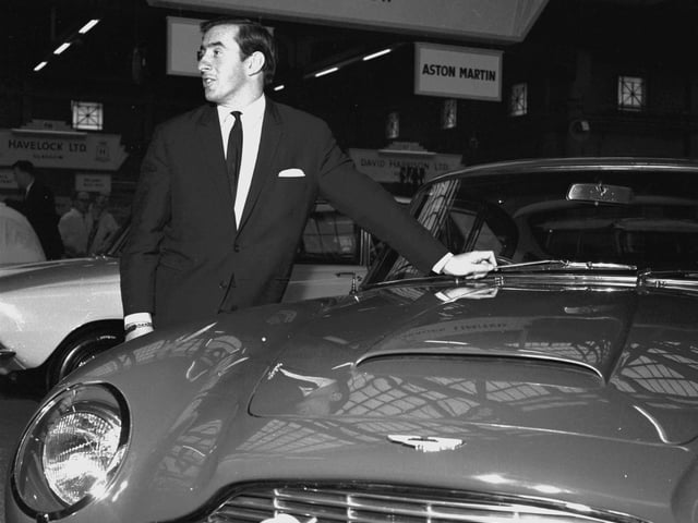 Racing driver Jackie Stewart stands beside an Aston Martin DB6 at the Scottish Motor Show in the Kelvin Hall, Glasgow, November 1965
