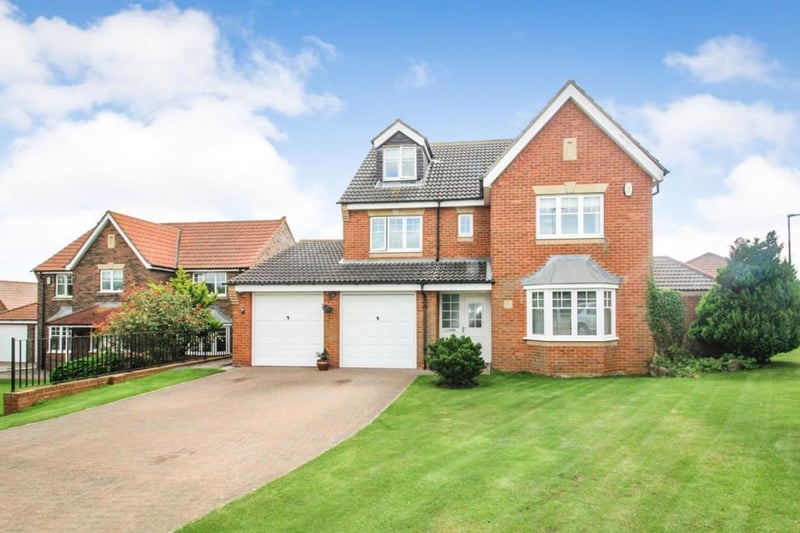 The large driveway leads to a double garage and is accompanied by a beautiful lawn.
