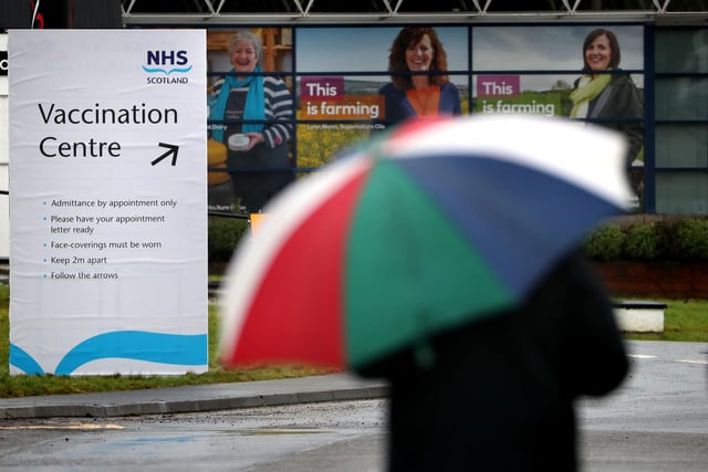 People walking by the Vaccination Centre sign at the Royal Highland Show ground.