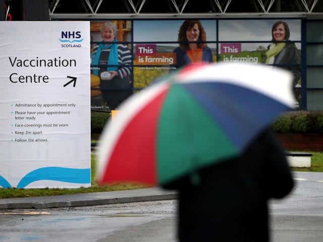 People walking by the Vaccination Centre sign at the Royal Highland Show ground.