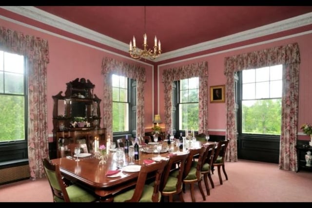 The grand dining room is an elaborate place for entertaining guests, with high ceilings, and many windows overlooking the beautiful surroundings.