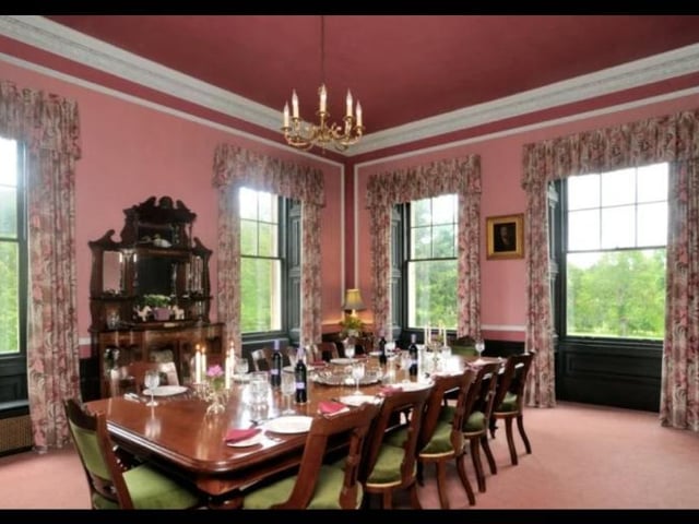 The grand dining room is an elaborate place for entertaining guests, with high ceilings, and many windows overlooking the beautiful surroundings.