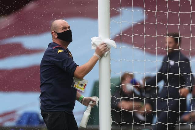A staff member disinfects a goal post  prior to the  English Premier League football match between Aston Villa and Sheffield United at Villa Park (Photo by CARL RECINE / various sources / AFP)
