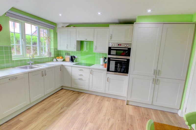 The kitchen has a superbly modern feel and has been fitted with attractive grey shaker style doors to the wall and base units, complemented by a lovely neutral work surface and an exquisite lime green glass splashback with matching tiles behind.