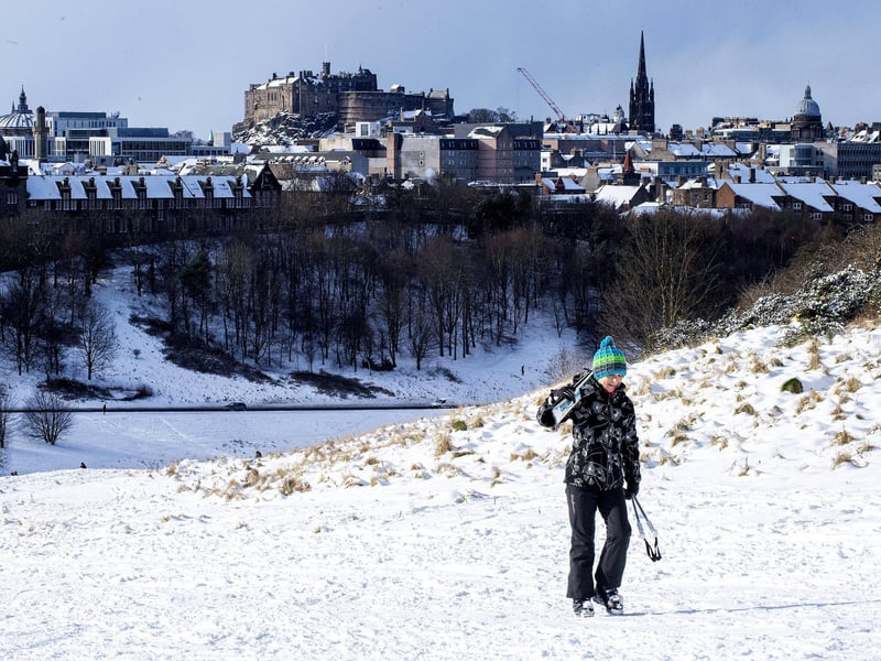 A skier carries their skis after a long day enjoying the snow.