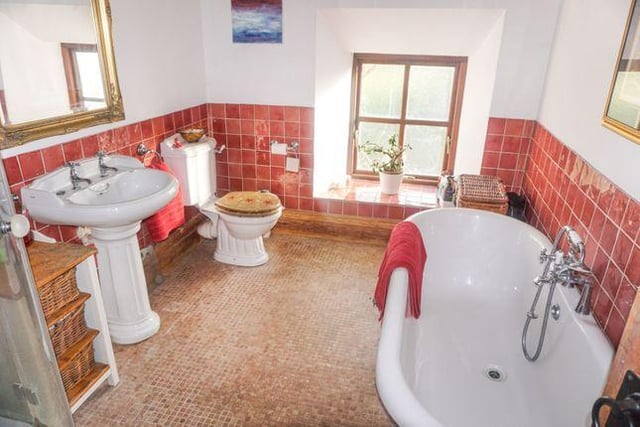 The family bathroom, one of five, consists of WC, handbasin, fully glazed corner shower cubicle along with a freestanding bath on a mosaic marble floor. Handmade glazed tiling is a feature on the walls.