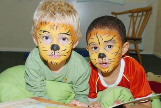 Children at Warren Day Nursery reading a book with their faces painted like tigers in 2007.