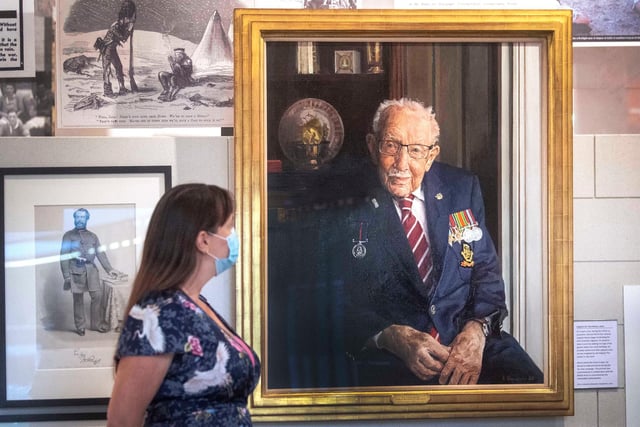 A staff member looks at a portrait of Captain Sir Tom Moore by artist Alex Chamberlin, as it is unveiled at the National Army Museum in Chelsea, London to mark the 75th anniversary of VJ day. PA Photo. Picture date: Friday August 14, 2020.