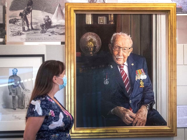 A staff member looks at a portrait of Captain Sir Tom Moore by artist Alex Chamberlin, as it is unveiled at the National Army Museum in Chelsea, London to mark the 75th anniversary of VJ day. PA Photo. Picture date: Friday August 14, 2020.