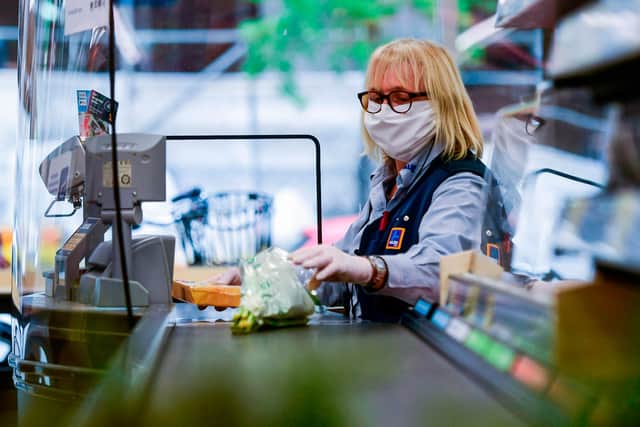 A cashier of food discounter ALDI wears a face mask as she serves a customer  (Photo by INA FASSBENDER/AFP via Getty Images)