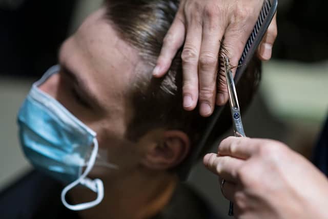 A man wearing a face mask is having a haircut in a hair salon  (Photo by SEBASTIEN BOZON/AFP via Getty Images)