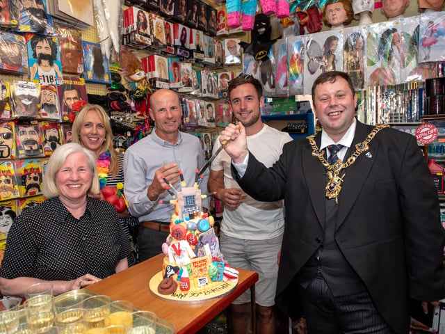 Lord Mayor Cllr Lee Mason prepares to cut the anniversary cake with the owners and staff of the shop