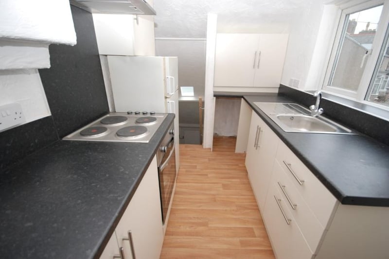 The kitchen is fitted with a range of wall and floor units with contrasting work surfaces.
