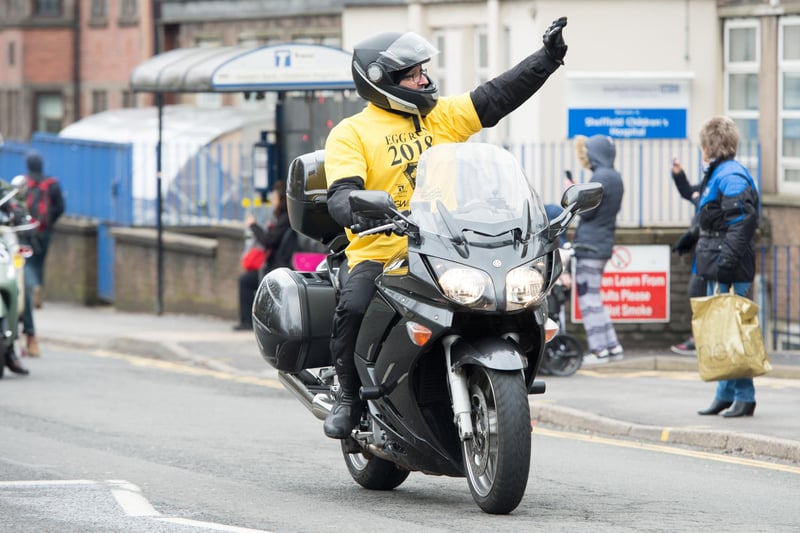 A rider waves to crowds outside Sheffield Children's Hospital.