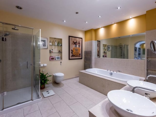 The en-suite bathroom is generous in size and features a large double end bath, twin Duravit wash basins set in a vanity unit, and an over-size walk-in shower.