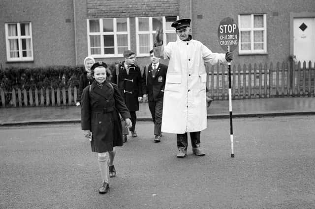 Traffic warden and lollipop man William Withnell shows children across Colinton Mains Road to Oxgangs Primary School in 1963.