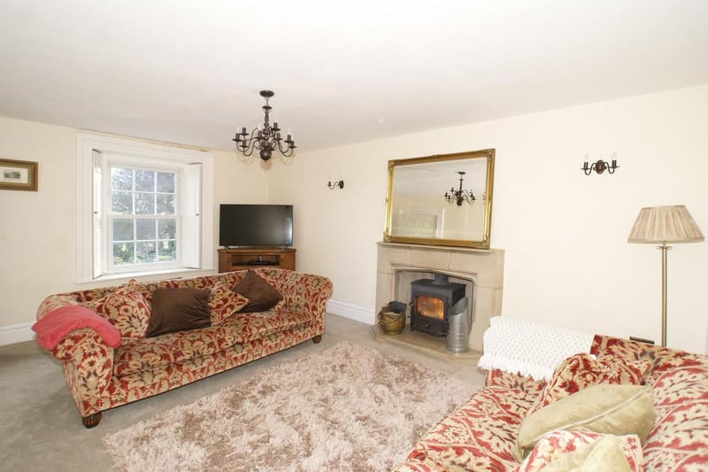 The drawing room boasts front-aspect UPVC double-glazed sliding sash windows with original fitted shutters. The room has a feature fireplace with a dressed stone surround and raised hearth housing a Clearview multifuel stove. There are wall and centre light points, and a television aerial point with satellite facility.