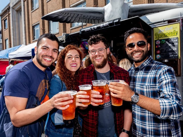 Southsea Food Festival 2019 at Palmerston Road, Southsea - Akshaya Chapagain, Marta Gallego, Edward Fraser and Rajeev Bhandari says cheers with their Hop House 13lager. All were students at University of Portsmouth five years ago and came back to Portsmouth to see each other and the city again. Picture: Vernon Nash 200719-015