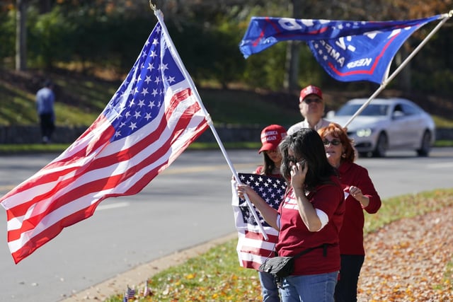 Supporters of President Donald Trump wave signs and flags at the entrance to Trump National golf club in Sterling, Va., Saturday Nov 7, 2020. He was at the facility. (AP Photo/Steve Helber)