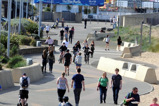 Crowds are pictured walking and cycling along the seafront.