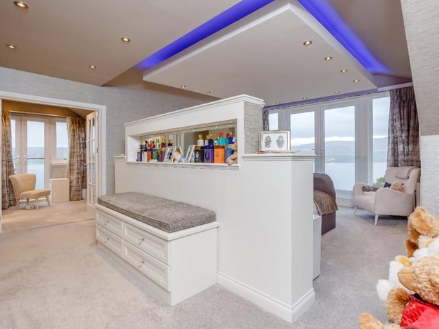The principal bedroom has bespoke central seating and full-height glazing incorporating French doors to a private glazed Juliet balcony with stunning loch views.