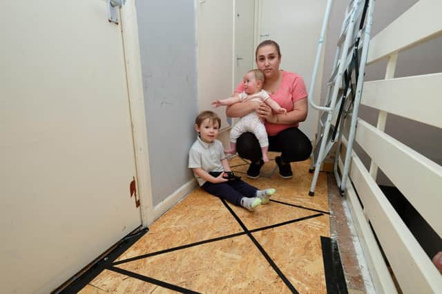 Dad Michael Bickerdike was hurt when he fell through ceiling in a Sheffield council house after concerns had been raised over water leaks. Partner Tanya Hearson is pictured with next to the boarded-up hole in the floor