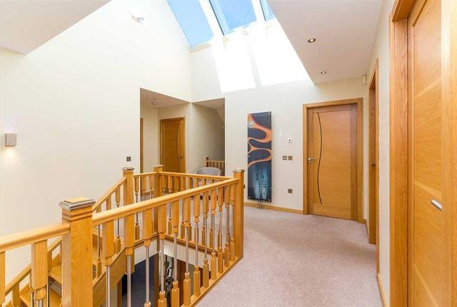 The upstairs areas of the house are accessed via an open-riser oak staircase, which leads up past a large window to a galleried landing