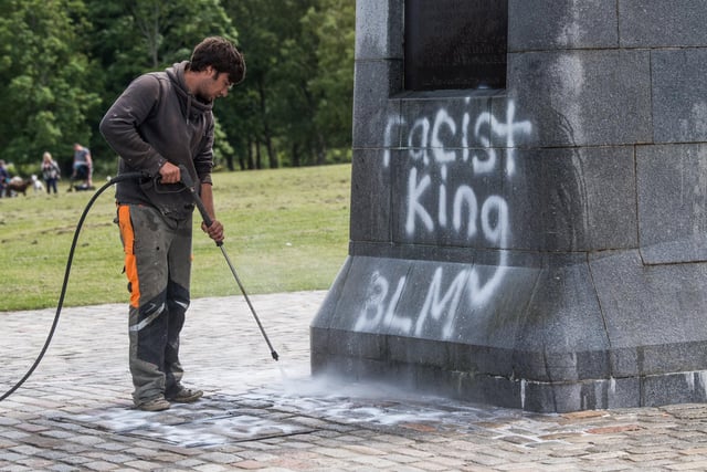 Workmen clean spray paint from the monument.