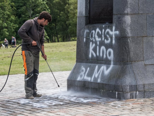Workmen clean spray paint from the monument.