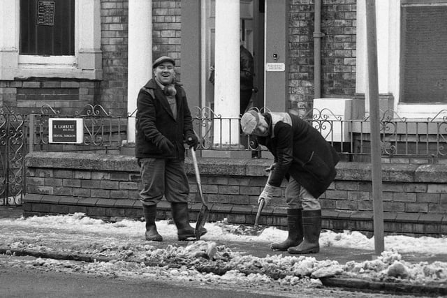 A cheerful council worker and colleague clearing away the snow and slush from footpaths in Grange Road in 1990.