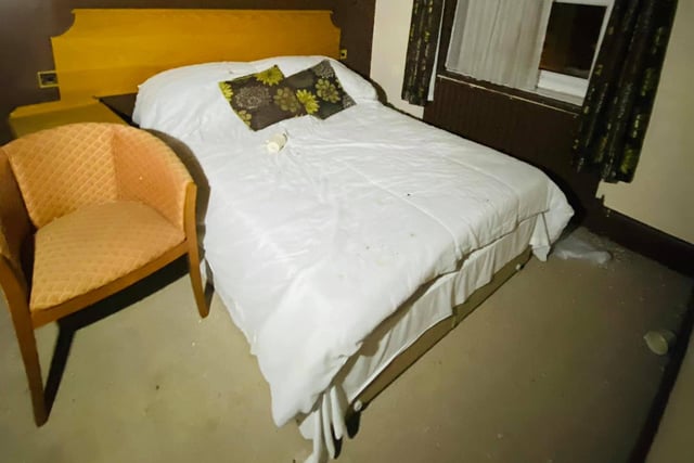 An abandoned hotel bedroom - complete with bedding and cushions.