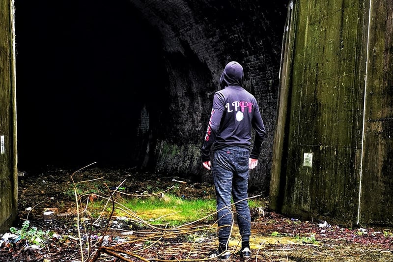 An urban explorer stands at the tunnel mouth.