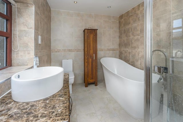 The en-suite comprises a beautiful Slipper bath with free-standing tap, a large shower cubicle with a waterfall showerhead over, a close coupled designer-looking WC with a lovely round sink on top of a solid wood vanity unit finished with a stunning brown granite surface.