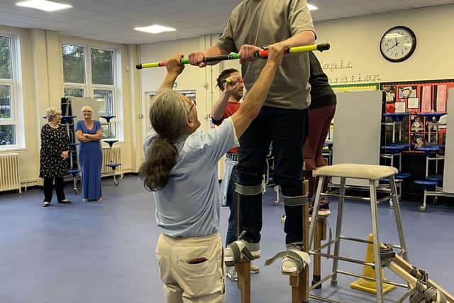 Matthew Walker gets some assistance as he takes his first stilt-walking steps
