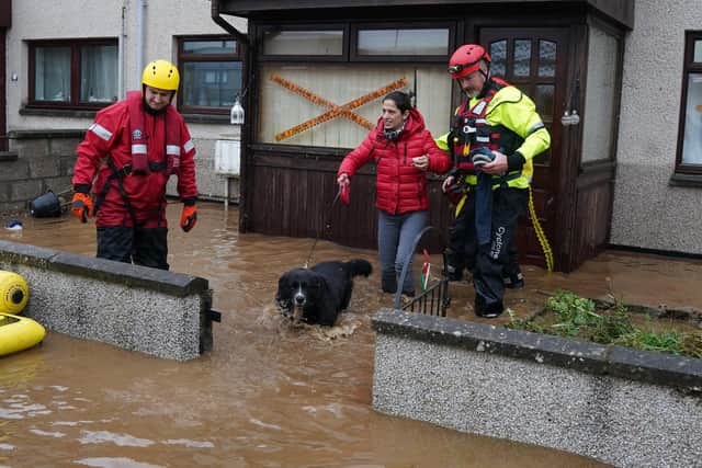 A member of the emergency services helps resident Laura Demontis from a house in Brechin, Scotland, as Storm Babet batters the country.