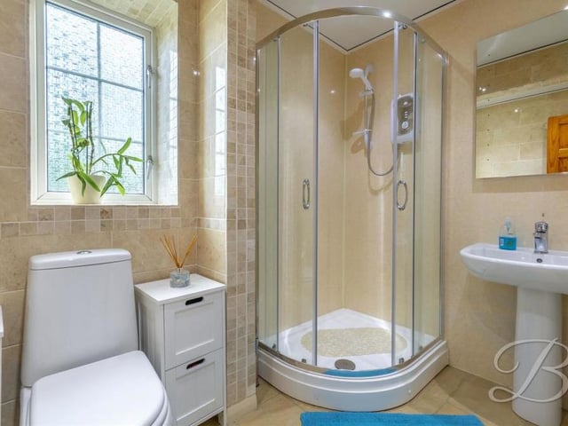 An enclosed shower is the highlight of the upstairs bathroom, which also features a low-flush WC, a pedestal sink and tiled flooring. There is also a WC downstairs.