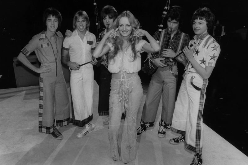 Model Twiggy blocks her ears against the sound of pop group Bay City Rollers having a go on the bagpipes at a TV show in 1976