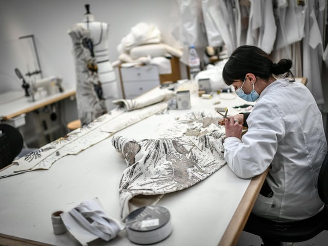 A seamstress works on a couture garment at Christian Dior's Haute Couture fashion house