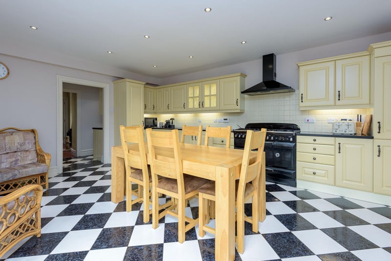 The large kitchen features stylish black and white tiled flooring, fitted cupboards with integrated appliances, a double oven and a spacious seating area.